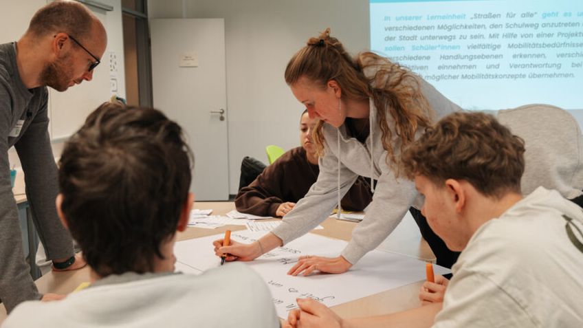 Vier Personen arbeiten schreibend an einem Tisch