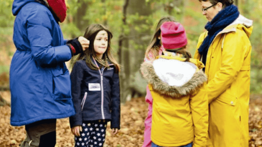 Zwei Erwachsene und drei Kinder stehen im Wald