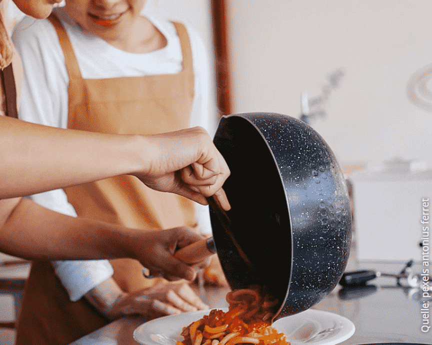 Zwei junge Personen füllen Spaghetti auf einen Teller © pexels antonius ferret