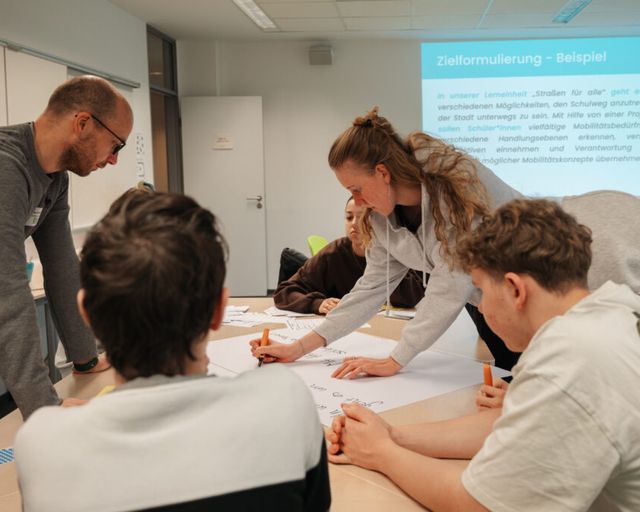 Vier Personen arbeiten schreibend an einem Tisch