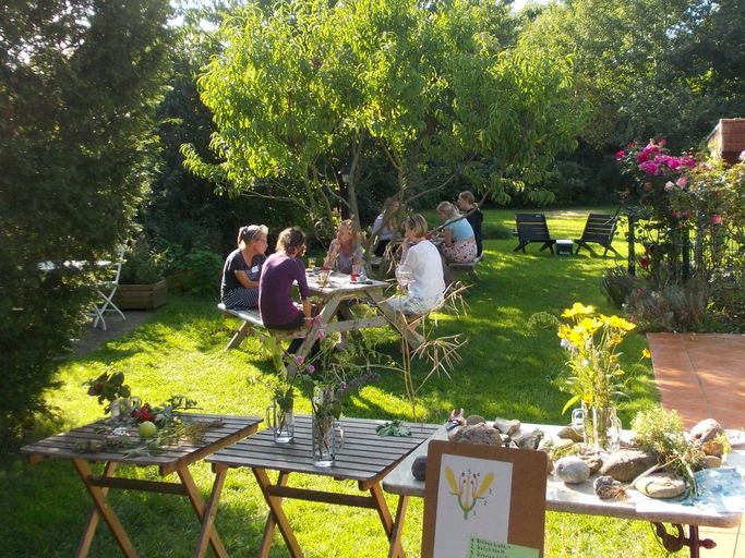 Grüner Garten mit Personengruppe am Tisch sitzend