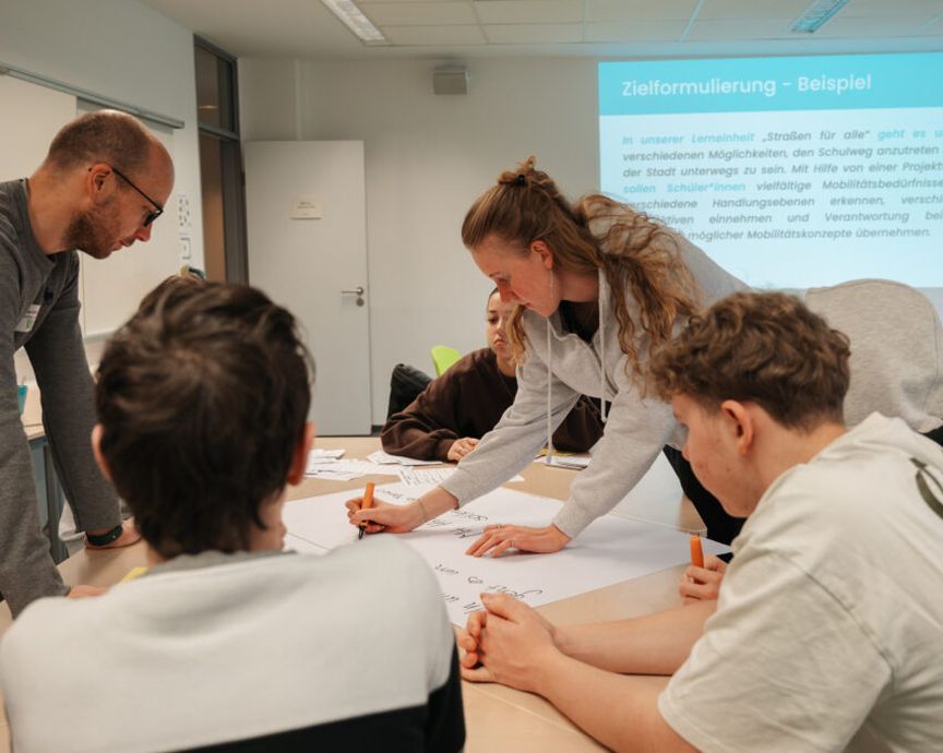 Vier Personen arbeiten schreibend an einem Tisch