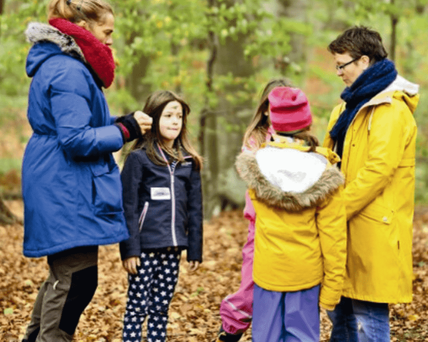 Zwei Erwachsene und drei Kinder stehen im Wald