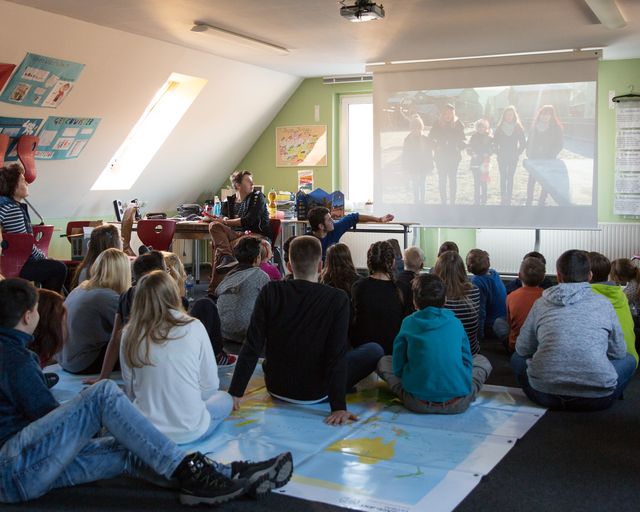 Gruppe Jugendlicher sitzt vor einer Leinwand