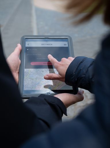 Eine Hand zeigt auf das Display eines Tablet-Computers