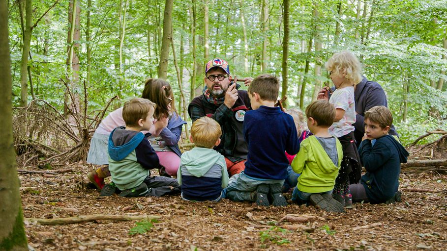 Personengruppe auf dem Boden sitzend im Wald