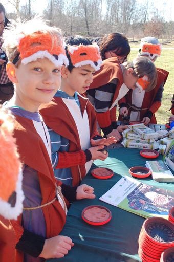 Eine Gruppe Kinder mit Fuchsmasken stehen um einen Basteltisch