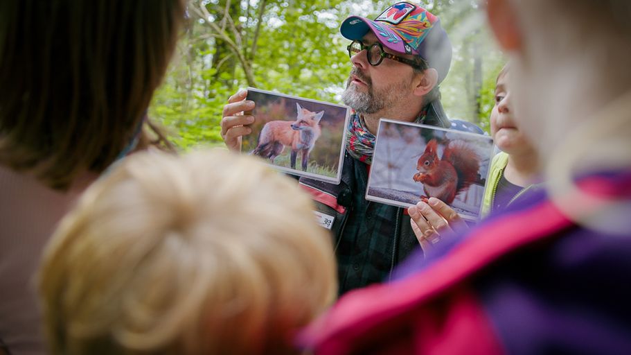 Mann im Wald zeigt Kindern ein Buch