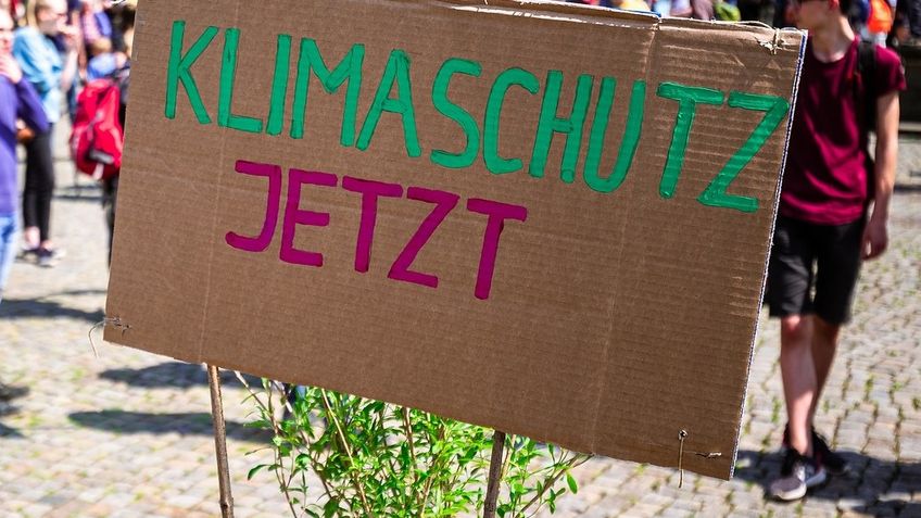 Auf der Vernetzungsveranstaltung rufen die Teilnehmerinnen mit Plakat zu "Klimaschutz Jetzt" auf